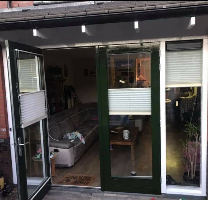 Openslaande deuren in donkergroen met witte kozijnen, van dichtbij. (jan 2021)