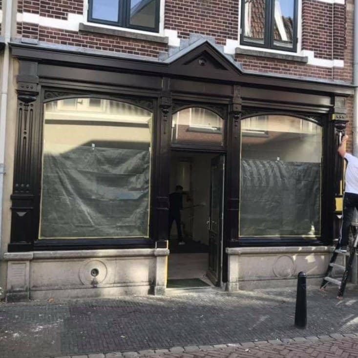 Bijna klaar: pui in de donkere kleur, schilder op de trap rechts bij de laatste pilaster. (jan 2021)