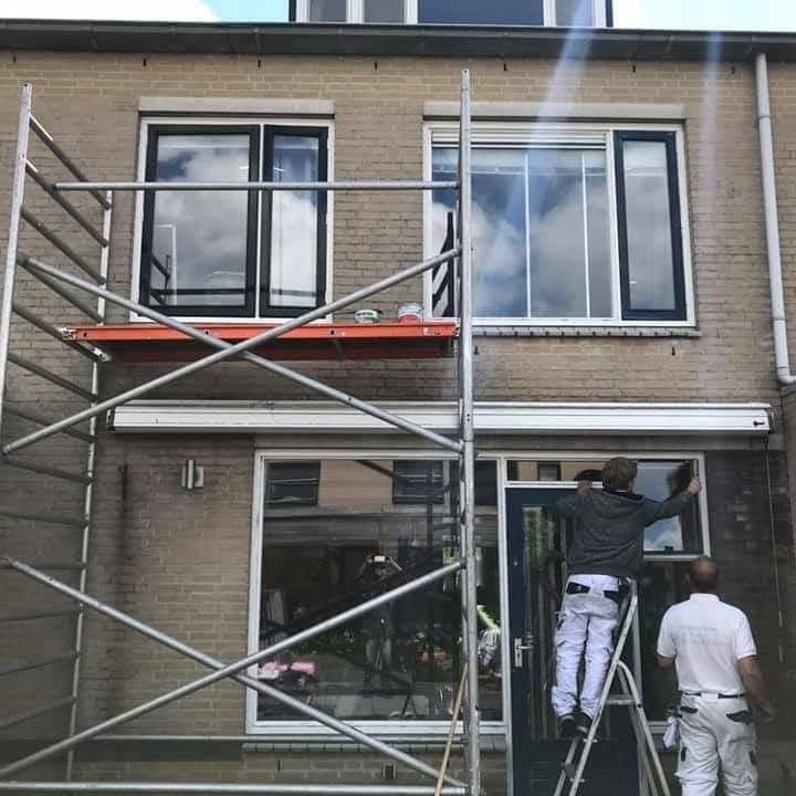 Tijdens het werk: rolsteiger voor de gevel, twee schilders bij de voordeur. (Facebook, 15 januari 2021)