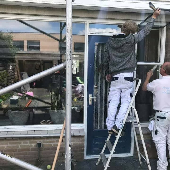 Tijdens het werk: twee schilders werken aan de voordeur en het kozijn. (Facebook, 15 januari 2021)