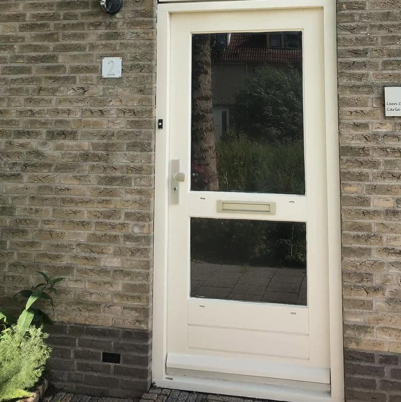 Na: crème voordeur met glas en brievenbus in een gele bakstenen gevel. (Facebook, 23 september 2024)