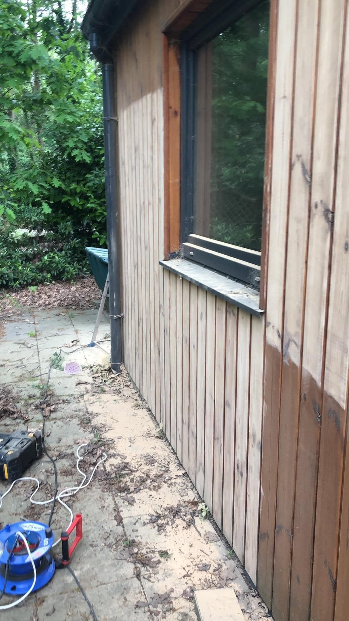 Verticale houten gevelbekleding naast een raam; het bovenste deel is licht, het onderste deel nog donker. (Facebook, 8 oktober 2024)